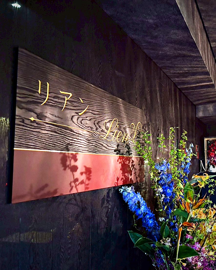 金の文字で「リアン Lien」と書かれた店内の看板と生花